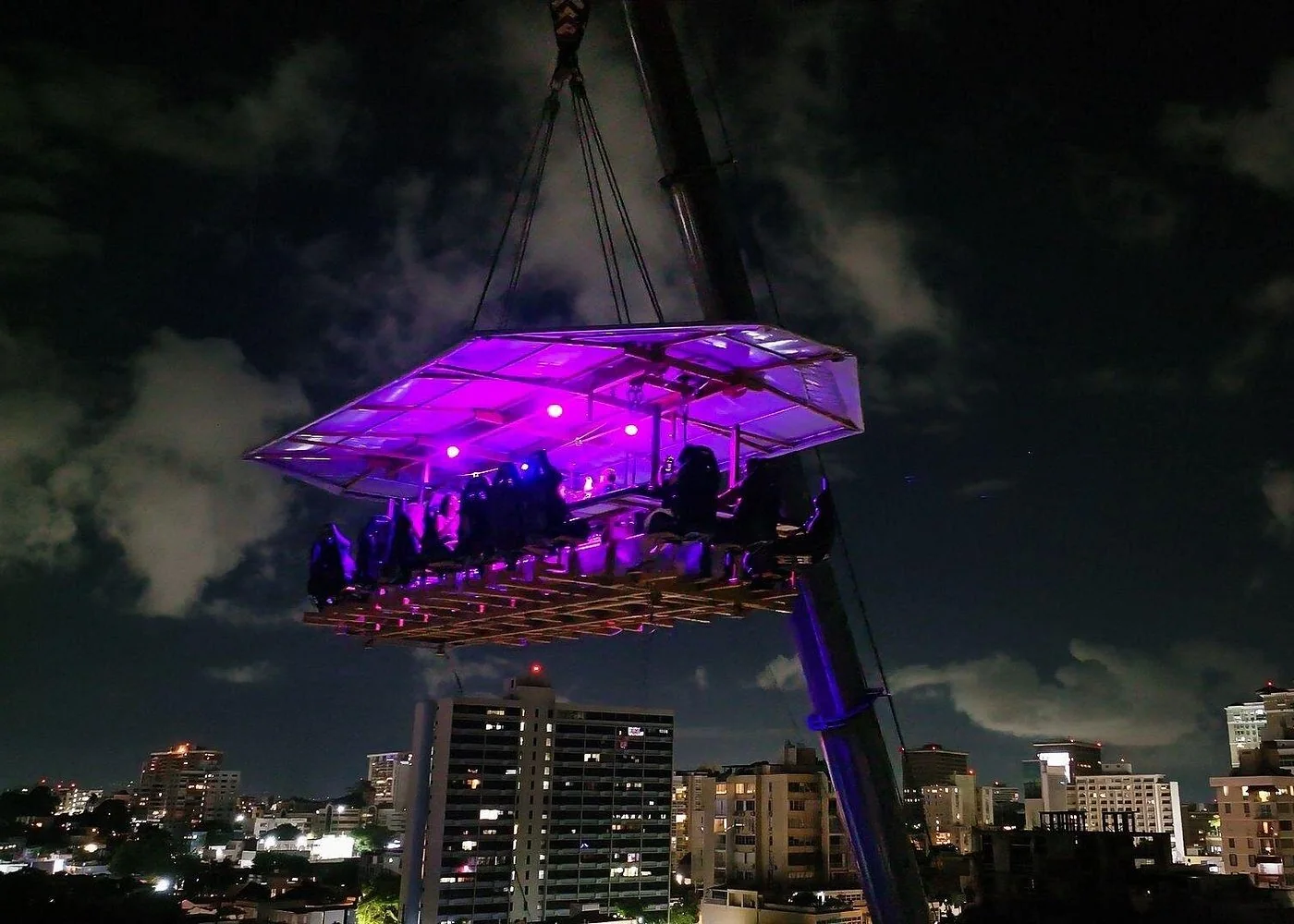 Purple-lit FlyDining platform above the San Juan skyline at night